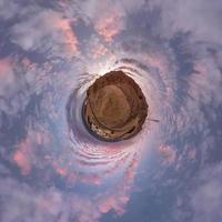 tiny planet in evening sky with beautiful clouds. Transformation of spherical panorama 360 degrees. Spherical abstract aerial view. Curvature of space. photo