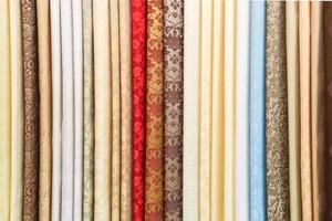 wide selection of different color textile silk fabrics clothes lay in row in drapery store photo