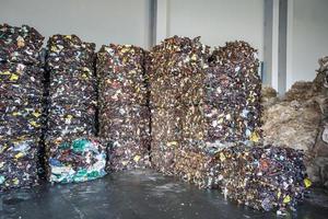 Stock of plastic brown pressed bales at the modern waste hazardous processing plant. Separate garbage collection. Recycling sorting and storage of waste for further disposal. photo