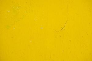 old wall painted with yellow paint with cracks and bubbles photo