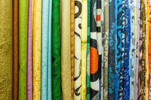 wide selection of different color textile silk fabrics clothes lay in row in drapery store photo