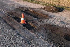 cono de peligro de tráfico naranja blanco en la reparación de carreteras de asfalto foto