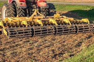 tractor cultivator plows the land, prepares for crops. dust on field photo