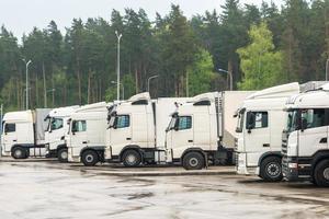 Trucks in a row with containers in the parking lot near forest , Logistic and Transport concept photo