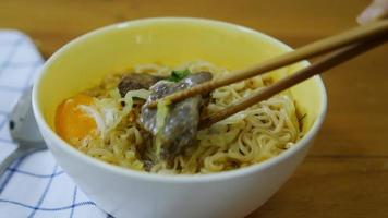 Lady eating instant noodle using chopstick cook with egg and pork and vegetable - quick noodle eating concept video