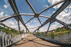 iron steel frame construction of pedestrian bridge across the river. wide angle view photo