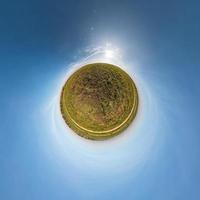 Little planet transformation of spherical panorama 360 degrees. Spherical abstract aerial view in field with awesome beautiful clouds. Curvature of space. photo