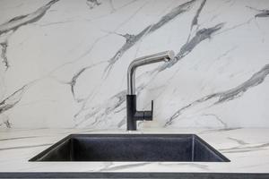 Black water tap sink with faucet in expensive kitchen photo