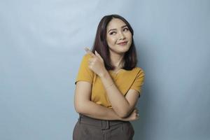 An excited young woman presenting and pointing upwards the copy space, isolated on blue background photo