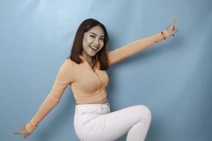 retrato de una joven y hermosa mujer asiática de pie y sonriendo a la cámara, aislada de fondo azul foto