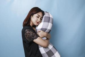 Portrait of sleepy attractive Asian woman wearing pajamas, holding bolster falling asleep photo