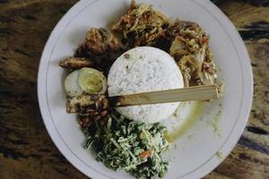 Nasi Campur Ayam Betutu. Balinese roast chicken stuffed with cassava leaves. Accompanied with steamed rice, Sate Lilit, Jukut Antungan, Lawar Nangka and Sambal Matah. photo
