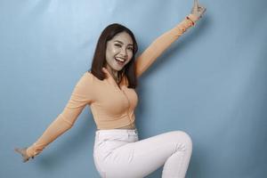 retrato de una joven y hermosa mujer asiática de pie y sonriendo a la cámara, aislada de fondo azul foto