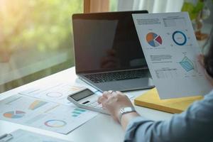 Portrait of a female accountant using a calculator and laptop to calculate balance using graphs for customers. photo