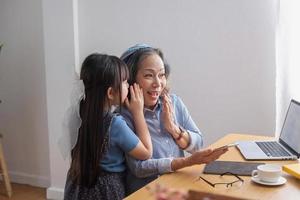 Portrait of an elderly woman and her granddaughter whispering to each other and doing family activities. photo