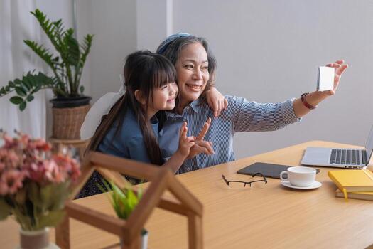 retrato de una anciana sosteniendo un teléfono celular para tomar una foto de ella y su nieta para futuras referencias.