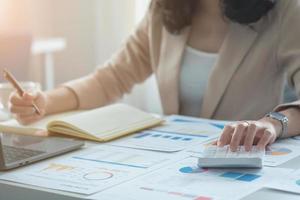 Closeup Portrait of a female accountant using a calculator and laptop to calculate balance using graphs for customers. photo