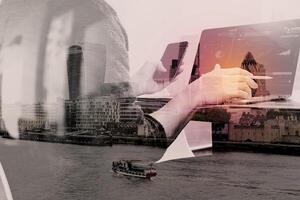 Double exposure of Designer hand using mobile payments online shopping,omni channel,laptop computer on wooden desk,London architecture bulidings photo