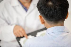 Selective focus of Boy doing eye test checking examination with optometrist in optics store, Optometrist doing color blindness disease perception test in optical shop photo