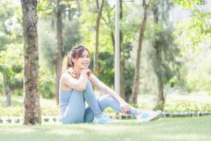 Cheerful young woman resting after exercising in the park, Happy free sportswoman sitting outdoors photo