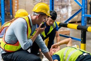 Manager and Workers taking care about their colleague lying on the floor in a warehouse, Warehouse workers man an accident lying on the floor in factory warehouse photo