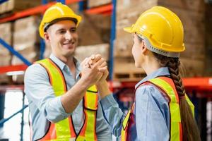 Warehouse workers soul brother handshake, thumb clasp handshake or homie handshake with blurred factory warehouse background, Success and Teamwork concepts photo