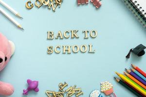 Laptop, notebook, note, pens, paper clip, on pastel blue background. Office desk with Back to school text. Flat lay photo