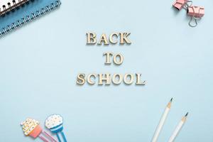 Office desk with Back to school text. Flat lay. Notebook, note, pencils, paper clip, on pastel blue background photo