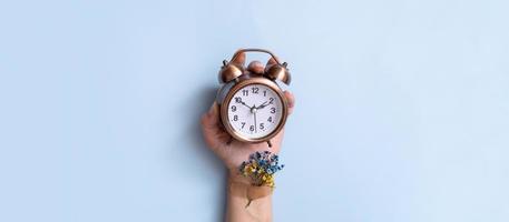 Ukrainian patriotism concept. Blue and yellow flowers and an alarm clock in a woman's hand and on a blue background photo