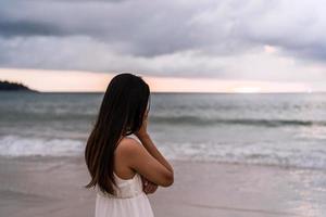 mujer joven que se siente sola y triste mirando el mar en un día sombrío foto