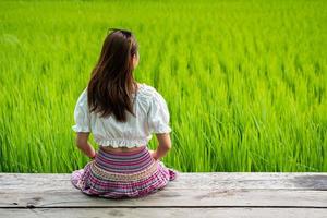 Young woman traveler sitting and relaxing with beautiful green paddy field photo