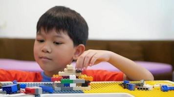le garçon joue au puzzle coloré de jouet en plastique pratiquant son cerveau
