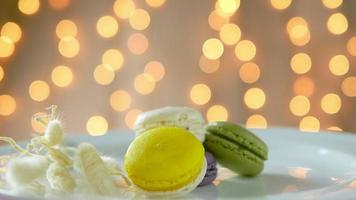 Colorful macarons in white plate with shiny bokeh background video
