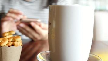 dame met behulp van mobiele witte koffie drinken in de coffeeshop video