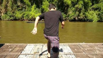 homem feliz pulando para o rio natural da jangada de bambu durante suas férias - as pessoas gostam de férias no estilo de viagem de água natural