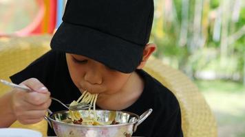 7 years boy eating spaghetti in outdoor restaurant video