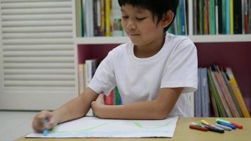 un niño asiático de ocho años está haciendo su tarea de colorear en casa video