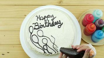 Woman is drawing chocolate cream on top of birthday butter cake decoration video