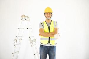 A view of the painter behind the wall painter with a paint roller and split bucket on a large empty space with a wooden staircase. photo