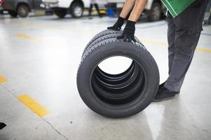 Technician holding a tire at a tire changing garage Set of four tires at a car service center photo