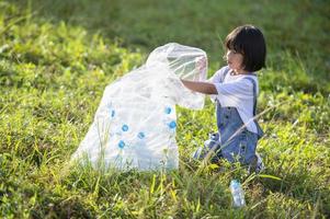 niños asiáticos se ofrecen como voluntarios para poner botellas de plástico en bolsas de basura. concepto de voluntariado y ecología foto