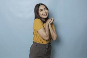 Pleased Asian woman reclines on her hands and looking at the camera over blue background photo