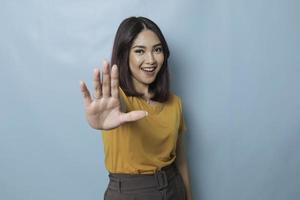 Young Asian woman wearing casual t-shirt over blue isolated background doing stop sign with palm of the hand. photo