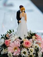 Wedding table decorations. Flowers, figurines of the bride and groom. photo