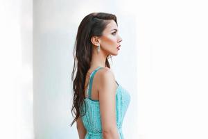 Portrait of a young pretty woman with turquoise dress on a white background. Profile Face photo