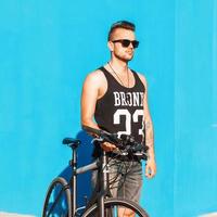 Young man with a bicycle near a bright blue wall. T-shirt with the numbers 23 photo