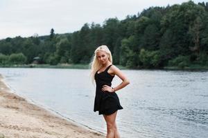 Beautiful girl in black dress on the river bank photo