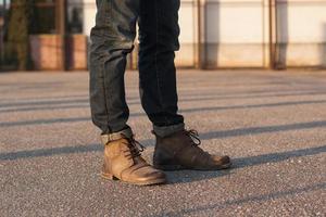 Men's legs with jeans and boots. Hipster at sunset. photo