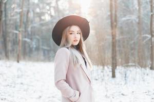 hermosa joven con estilo en un sombrero negro de moda y abrigo en el día soleado de invierno. foto