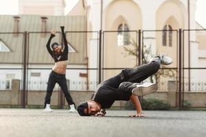 joven y guapo bailarín bailando hip-hop. mujer bonita bailando en el fondo. foto